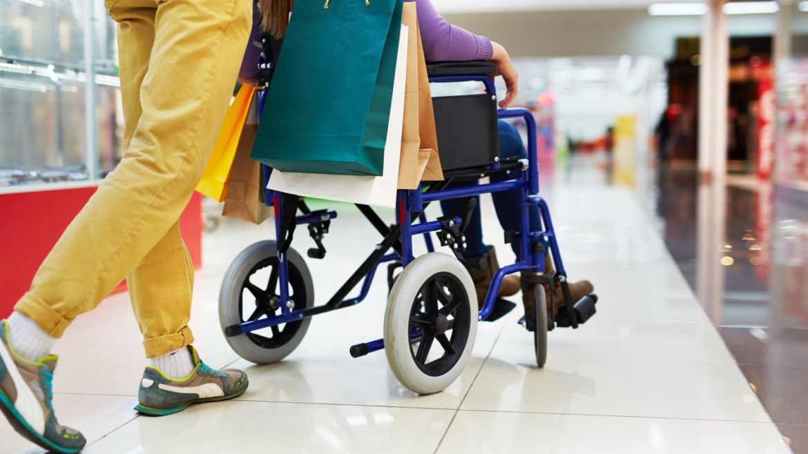 caring guy helping his girlfriend on wheelchair with shopping